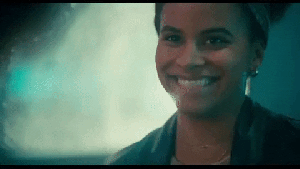 Sophie is a young Black woman. She has her hair up. She is breaking into a laugh