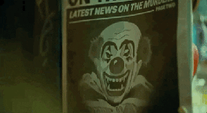 Arthur is looking at a newspaper front page. It shows the drawing of a clown with large fangs. Arthur widens his mouth in a growl