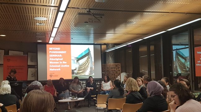 A room full of majority women watch a mix of Aboriginal and non-Indigenous women panellists at the Sydney Law School