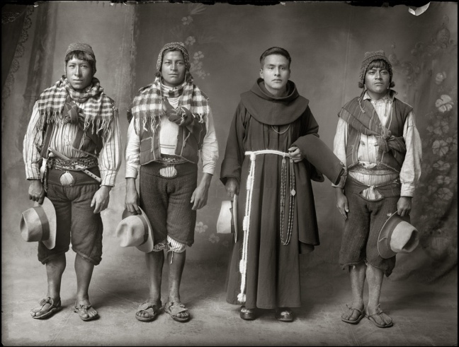 A mestizo priest stands in between three Quechuan men