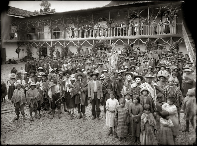 Dozens of Quechuan villagers stand in front of a colonial building