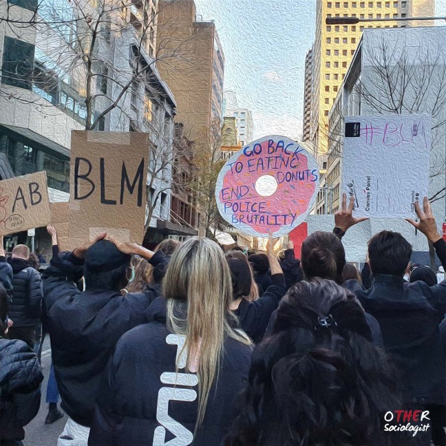 Protesters march in Sydney. They hold up signs saying "BLM" and "Go back to eating donuts. End police brutality"