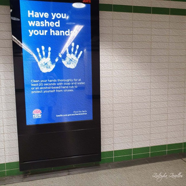 Oil painting of a subway sign about COVID-19. It shows an imprint of two hands. The message reads: have you washed your hands?