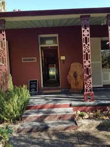 The front door has beautiful Aboriginal artworks and woodwork and a green shrub
