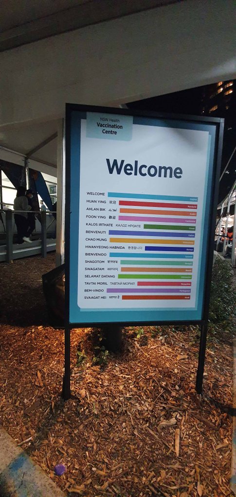 "Welcome" sign near the entrace of the mass vacination site, translated into many languages